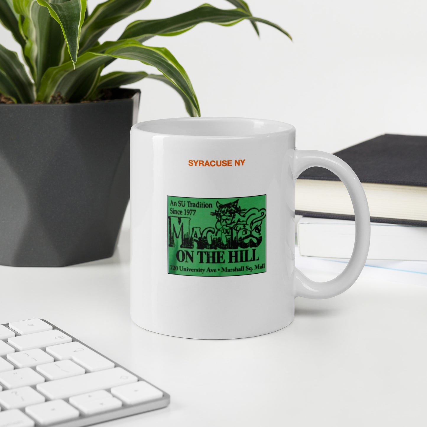 White mug that says 'Syracuse NY' in orange and 'Maggie's on the Hill' in green and black